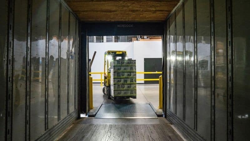 A manual forklift carrying a load of pallets.